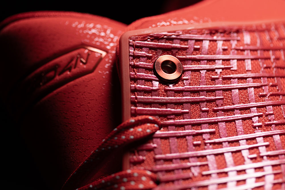 Metal rivet eyelet set directly into the nano print mesh of the Air Jordan 41 Ruby beside reflective-fleck laces