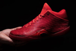 Air Jordan 41 Ruby held in hand against a black background, showing the nano print mesh upper and translucent red midsole
