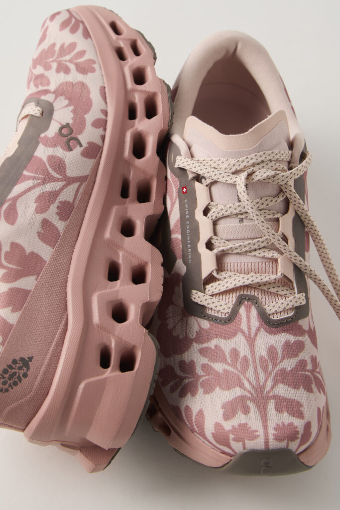 On x FP Movement Cloudmonster 3 in Dusty Rose, one shoe on its side showing the CloudTec pods and one upright showing the floral jacquard upper