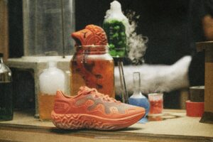 PUMA x Salehe Bembury Velum 2 NITRO in Red Clay-Nasturtium on a laboratory bench surrounded by beakers