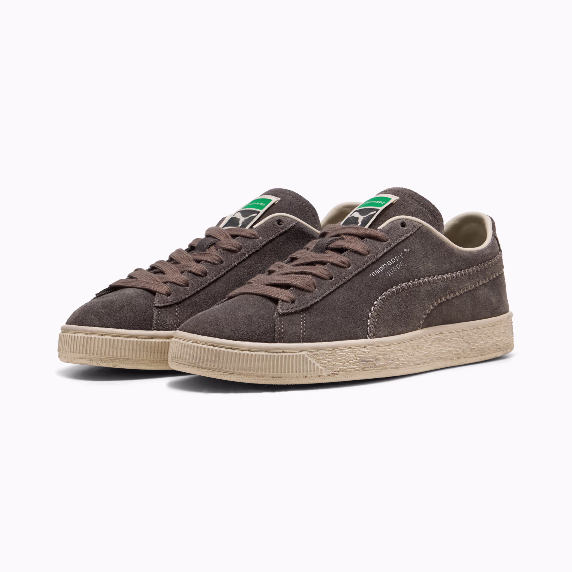 PUMA x Madhappy Suede pair in Matte Bronze and Alpine Snow seen from the front, dark grey-brown suede uppers on cream foxing with green PUMA tabs at the collar